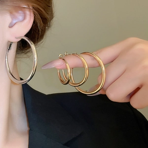 Polished silver and gold hoop earrings in multiple sizes shown on hand and ear