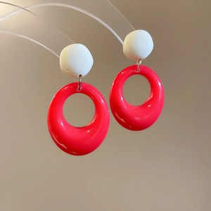 Vue macro de boucles d'oreilles ovales en résine bicolores blanc et magenta vif