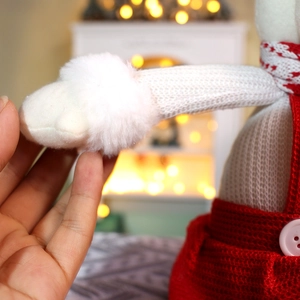 Gros plan d'une poupée de Noël tricotée avec fourrure synthétique et lumières festives