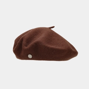 Detailed macro of dark brown wool beret featuring a vintage silver metal logo emblem