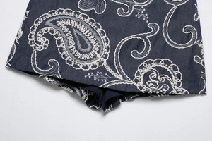 Detail of white paisley embroidery on dark blue fabric showing high quality stitching