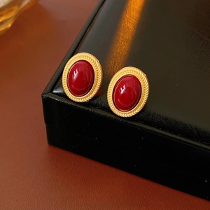 Vintage red oval gemstone earrings in textured gold setting displayed on jewelry case