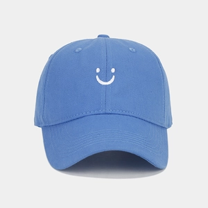 Detailed close-up of sky blue cotton baseball cap with white smile face embroidery