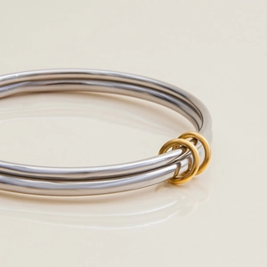 Détail macro d'un bracelet bicolore en acier inoxydable poli argenté et doré entrelacé
