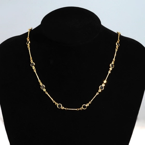 Detailed close-up of golden metal necklace with black round gemstones on a velvet bust