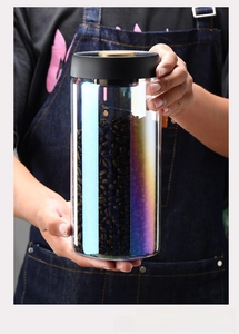 Iridescent glass storage jar with black vacuum seal lid for coffee beans shown in hand