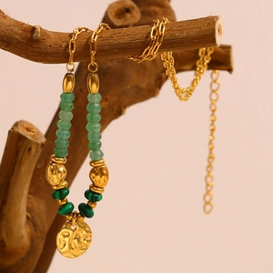 Collier doré martelé avec perles vertes suspendu à une branche naturelle, style élégant