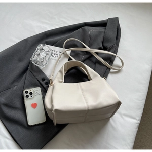 Detailed macro view of cream white litchi pattern leather bag on a grey casual blazer