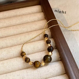 Close-up of brown tiger eye beads and gold spacers on a fine gold-colored chain.