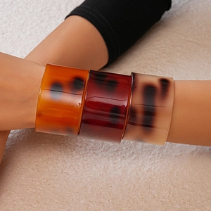 Detail view of wide acetate bangle with amber and cream tortoiseshell patterns on wrist