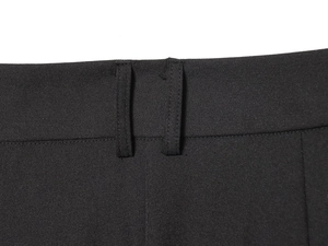 Détail de la taille du pantalon noir montrant les passants de ceinture et le tissu