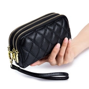 Dettaglio della pochette nera con doppia cerniera dorata e motivi trapuntati