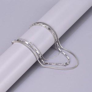 Detailed macro view of triple-layered silver stainless steel necklace on a gray display stand