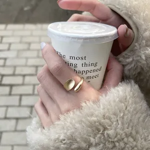 Detail of matte gold oval pea open ring worn with a winter outfit and coffee cup