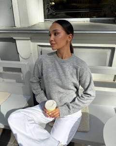 Close-up of gray knit sweater showing texture, crew neck and split hem details