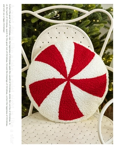Close-up of a red and white spiral candy plush pillow on a white chair with Christmas tree