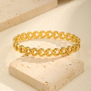Close-up of golden stainless steel hollow heart-shaped link bracelet on a textured stone