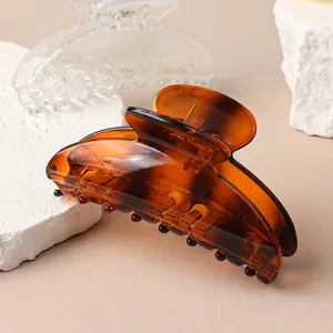 Elegant amber tortoise shell hair claw clip for women on a white stone background