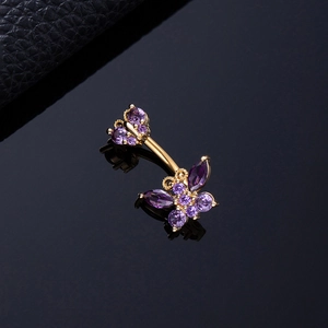 Macro shot of gold belly ring featuring purple zircon butterflies on a black surface