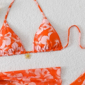 Detail of tropical floral bikini top with a decorative golden flower pendant