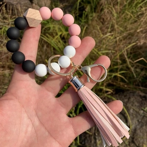 Detailed view of pink and black silicone bead keychain with leather tassel and wood charm