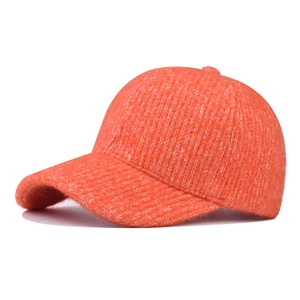 Close-up of vibrant orange knitted baseball cap showing thick textured yarn and stitching