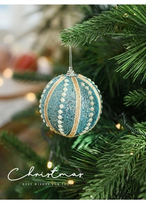 Blue glitter Christmas ball with white pearls and twine hanging on a festive tree