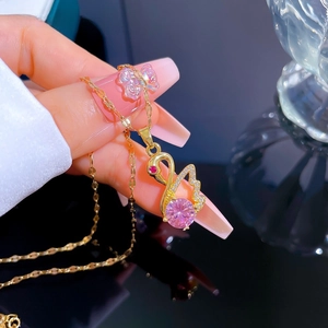 Macro shot of gold swan pendant necklace featuring pink gemstone and cubic zirconia accents