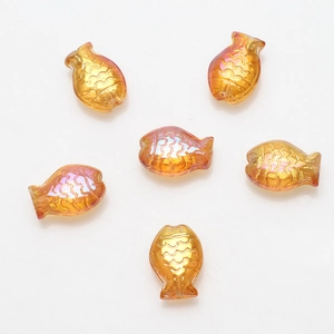 Macro detail of orange fish-shaped glass beads with iridescent rainbow coating