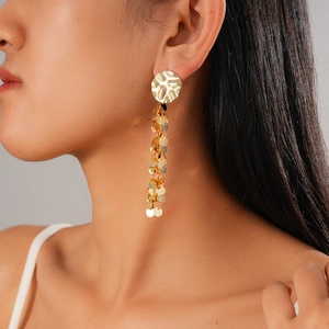 Close-up of gold layered sequin tassel earrings with irregular hammered texture detail