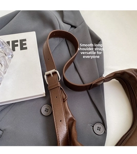 Detail of adjustable leather strap with silver buckle on brown shoulder tote bag