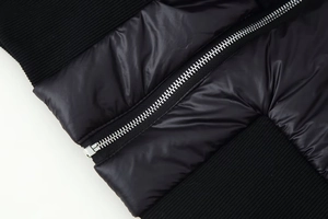 Detailed macro shot of silver metal zipper and quilted texture on black padded jacket