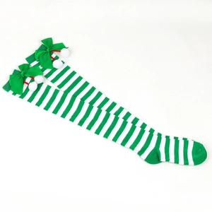 Detail of green and white striped Christmas over-knee socks with satin bow and pom-poms