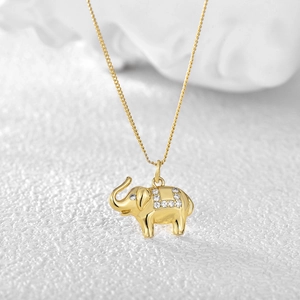 Collana dorata con ciondolo a forma di elefante e zirconi bianchi su sfondo bianco materico