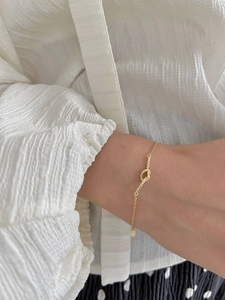 Detailed view of a gold S925 sterling silver twisted knot bracelet on a female wrist