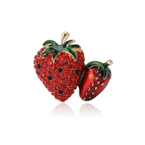 Sparkling red strawberry brooch with rhinestones and gold leaves on white background
