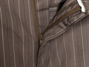 Détail du pantalon marron à rayures montrant la fermeture éclair et le tissage précis