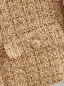 Detailed close-up of apricot tweed fabric with gold metallic thread and matching button