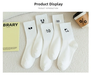 Close-up of white cotton crew socks featuring various funny facial expression embroidery
