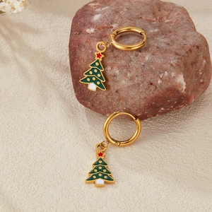 Macro shot of gold Christmas tree earrings with enamel detail on natural stone base