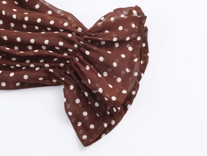 Dettaglio della manica in chiffon marrone a pois bianchi e polsini con volant