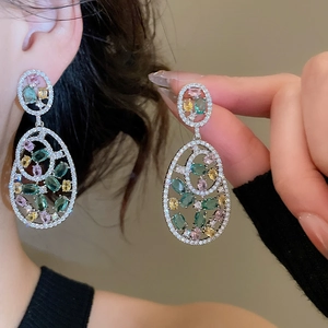 Macro shot of silver stud earrings with vibrant green and pink oval gemstones