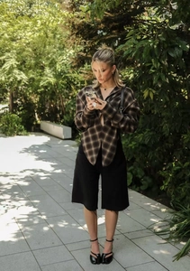 Outdoor shot of a casual plaid long-sleeve shirt with black shorts and tabby sandals