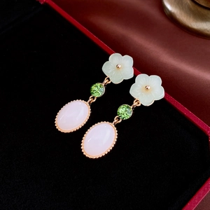 Detailed macro view of Chinese style floral earrings with resin jade and green gems
