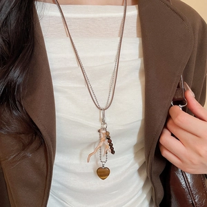 Close-up of double-layer vintage necklace with heart pendant and coral charm on a model