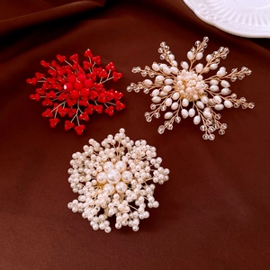 Dettaglio di spille a fiore con perle fatte a mano in rosso e bianco su velluto
