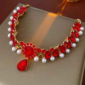 Detail of vintage gold necklace with red rhinestones and elegant white pearls