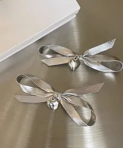 Detail of silver metallic bow hair clips with heart charms on aesthetic props