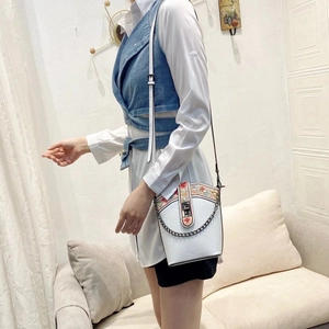 Detail of white embroidery bucket bag with floral flap and decorative black chain strap