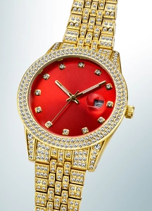 Close-up of luxury gold-plated watch with red dial and full diamond-set iced out bezel